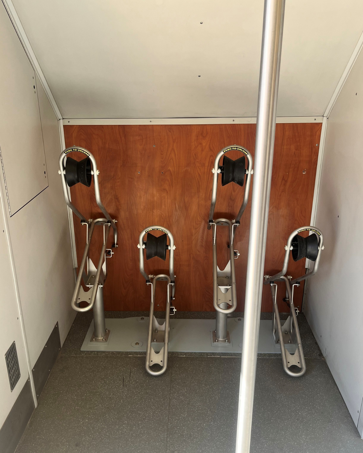 Picture of four metal silver and black bicycle racks installed on the Rail Runner train