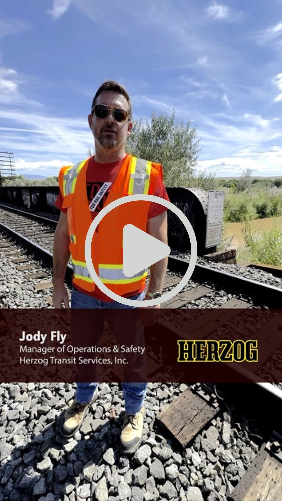 Picture of a transit safety professional in an orange vest near a railroad bridge